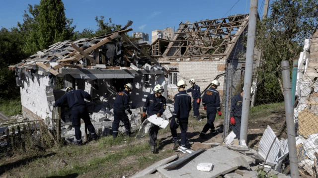 Bomberos ucranianos retiran escombros de una casa bombardeada.