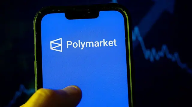 Un celular muestra en la pantalla el logo de Polymarket.