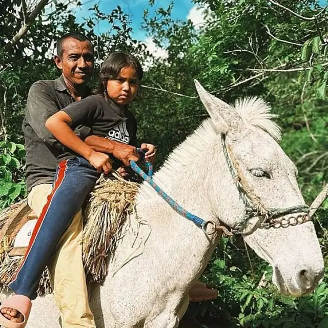 Ana junto a padre montados en un caballo blanco rodeados de vegetación