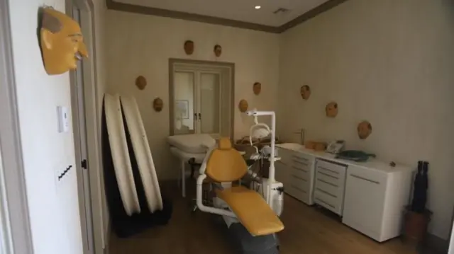 Otra habitación tiene una silla de dentista y máscaras en la pared.