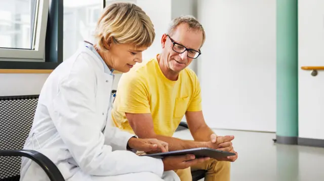 Una médica conversa con un paciente en una consulta.
