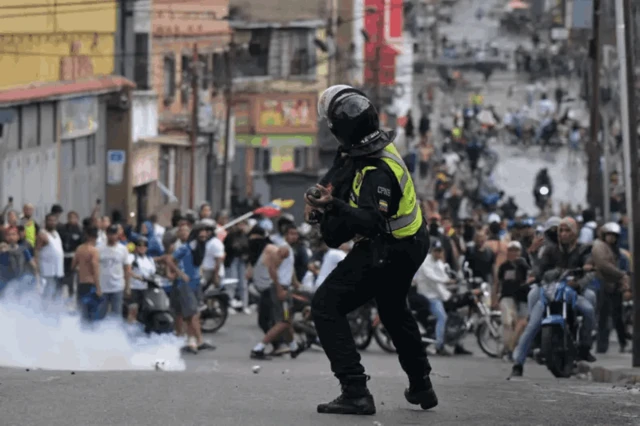 Un policía lanzando una bomba de gas a manifestantes