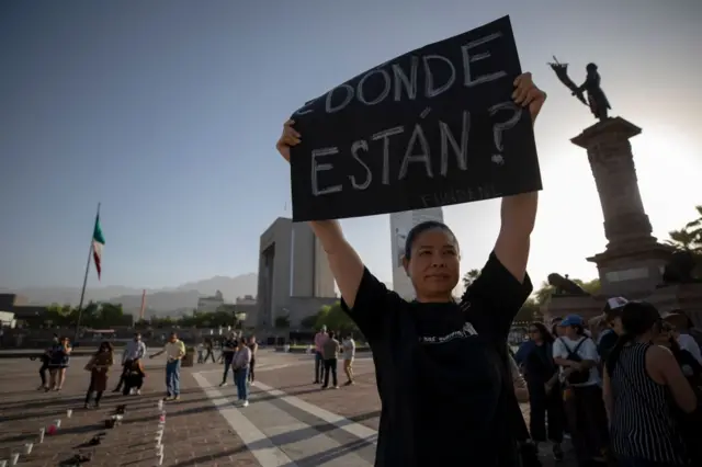 Una mujer sostiene un cartel en el que se lee: ¿Dónde están?