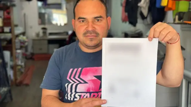 Trabajador de una papelería con una fotocopia de una cédula. 