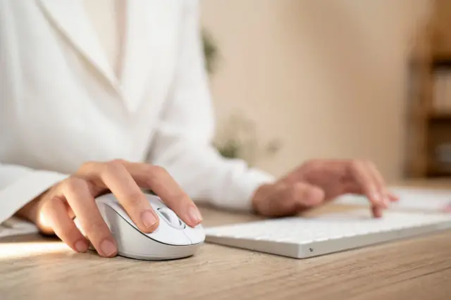 Mano de una mujer usando un mouse blanco