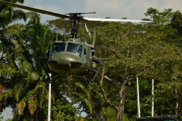Un helicóptero del ejército colombiano en vuelo, con un tirador asomado a uno de los laterales.