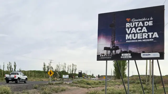 Ruta por donde pasa una camioneta y hay un cartel que dice Vaca Muerta.