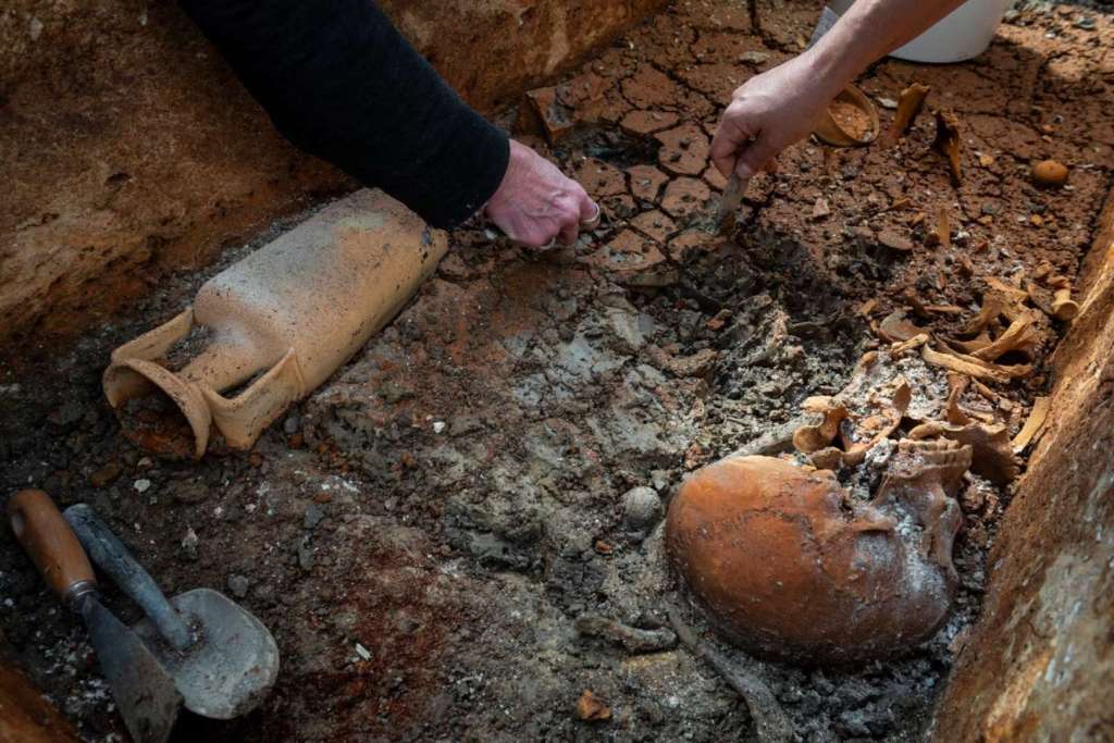 En esta imagen difundida por el Museo de Historia de Budapest, varios investigadores retiran cuidadosamente la capa de arcilla que cubre un sarcófago romano intacto en pleno yacimiento arqueológico