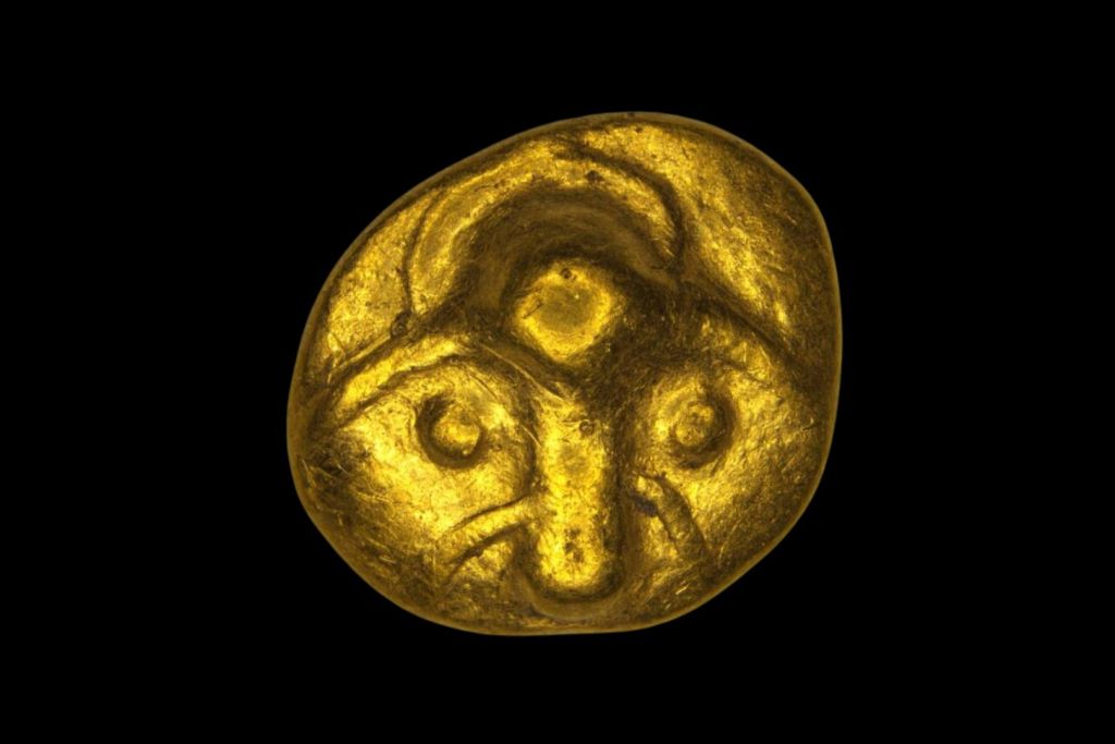 El rostro representado en el anverso de la antigua moneda muestra una frente prominente, una nariz alargada y lo que parecen ser cuernos estilizados